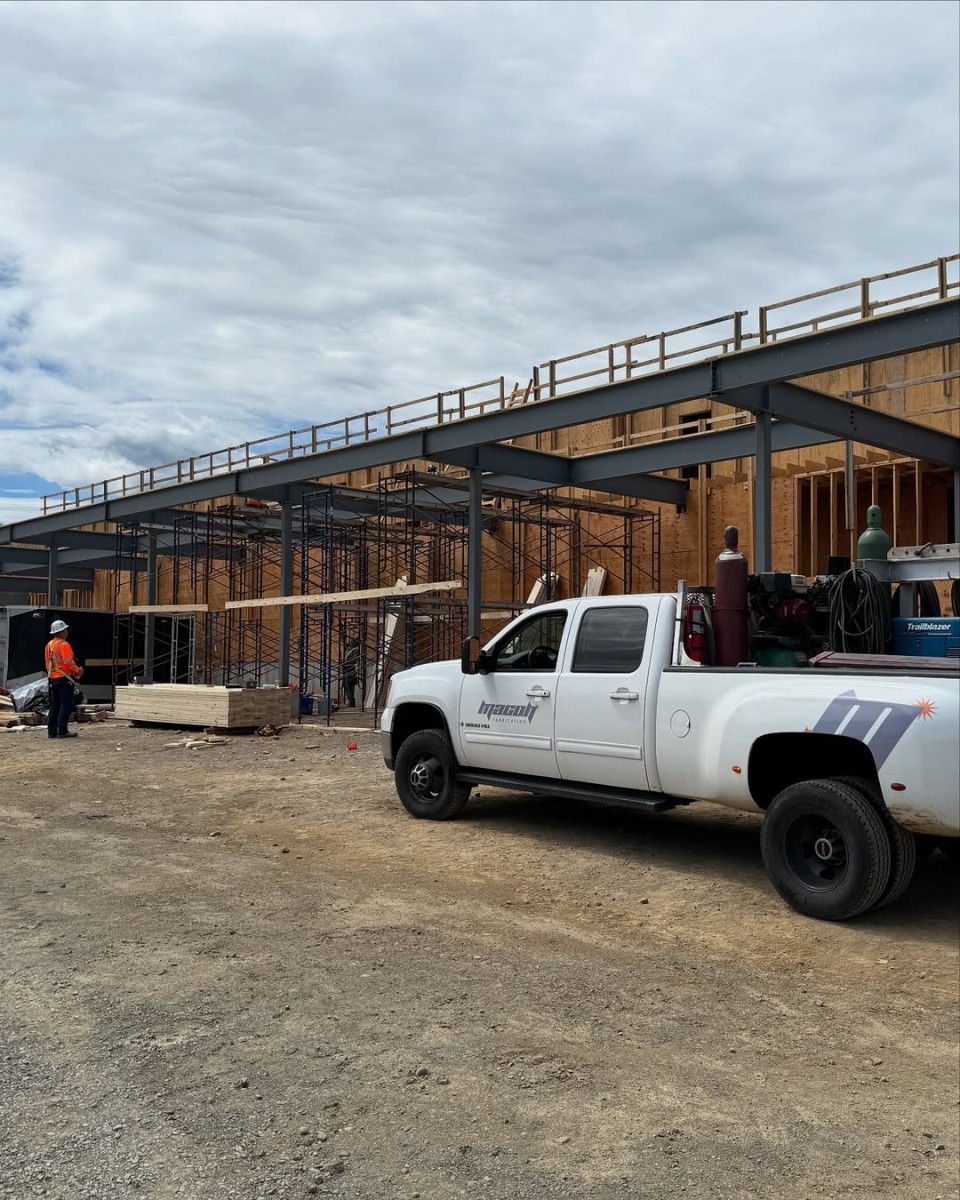 Steel structure under construction with scaffolding and a Macon Fabrication mobile welder truck on site